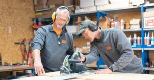 Zwei Handwerker in einer Werkstatt beim Sägen